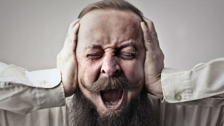 Mann hält sich die Ohren zu